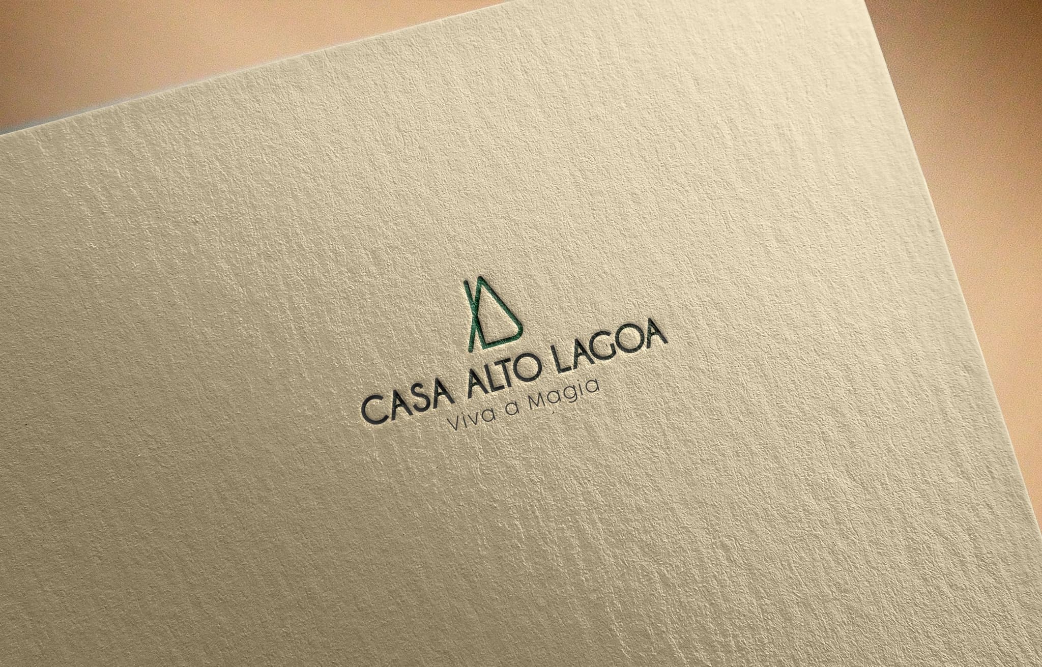 Símbolo e logotipo Casa Alto Lagoa com a assinatura Viva a Magia gravados em papel texturizado