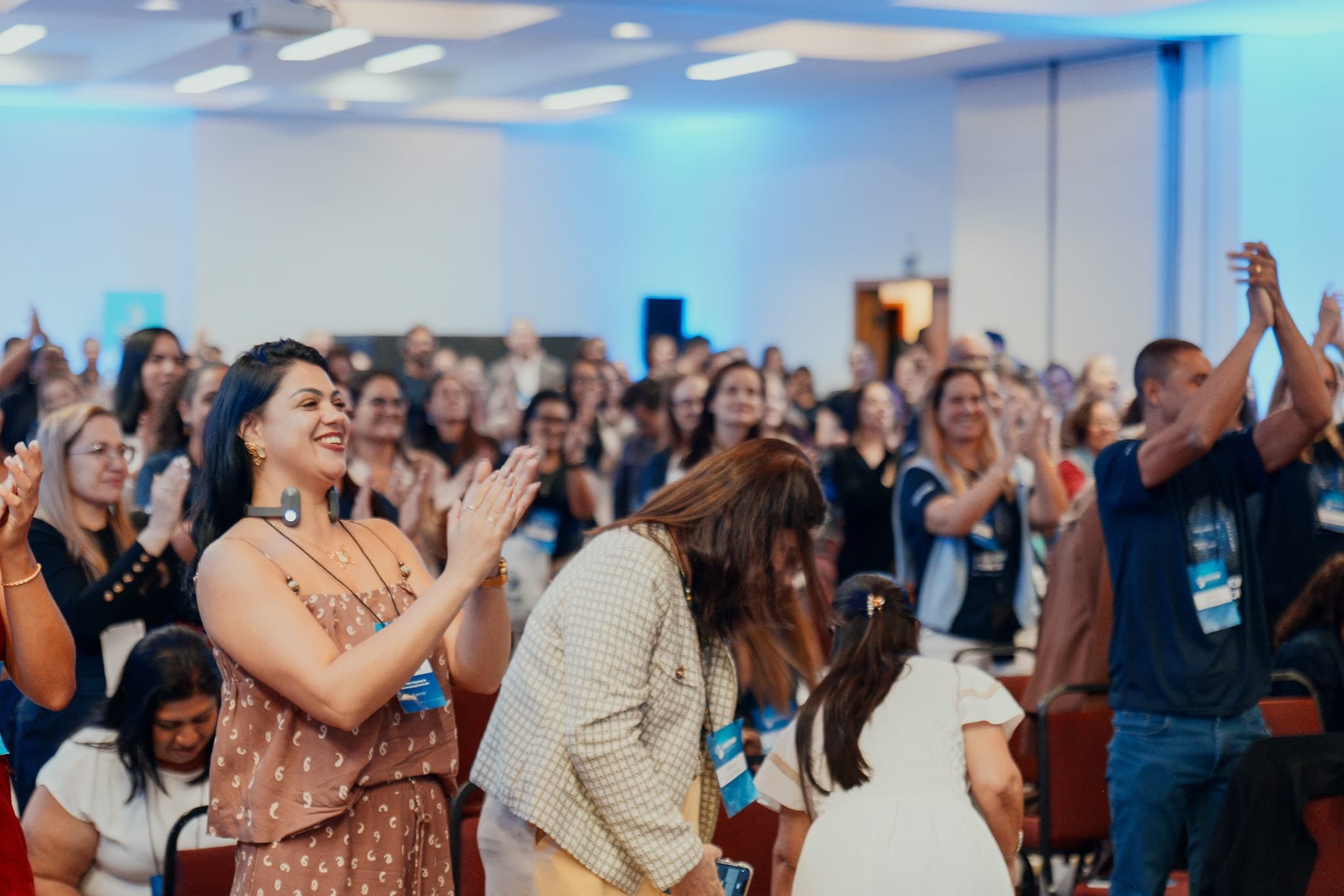 Participantes de pé aplaudem e interagem durante uma dinâmica do congresso