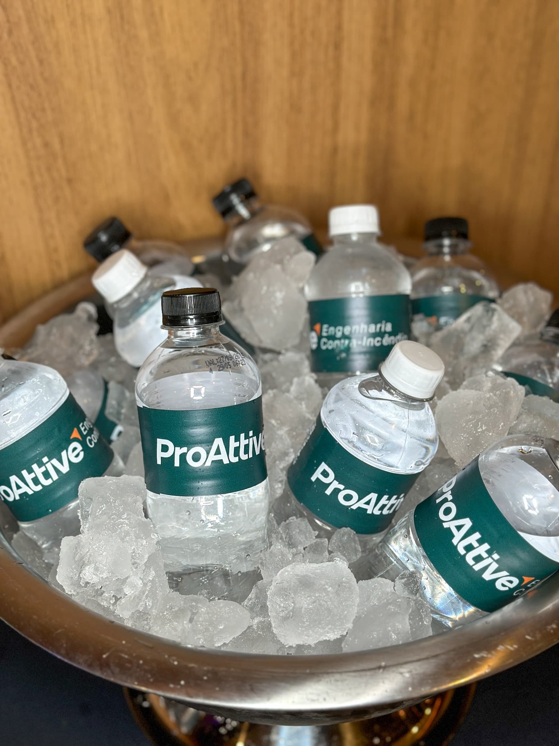 Garrafas de água com a marca Proattive em balde de gelo na recepção do fórum