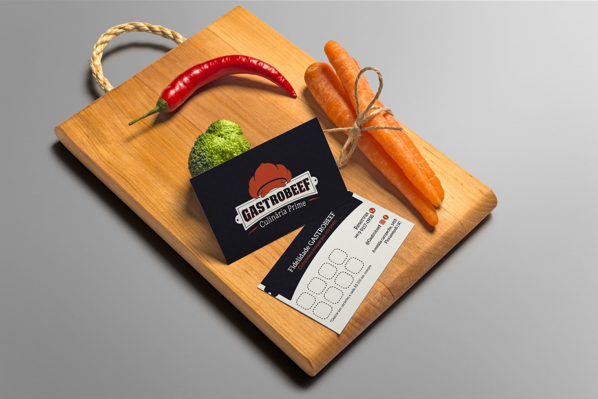 Cartão-fidelidade da GastroBeef sobre tábua de madeira com pimenta e legumes