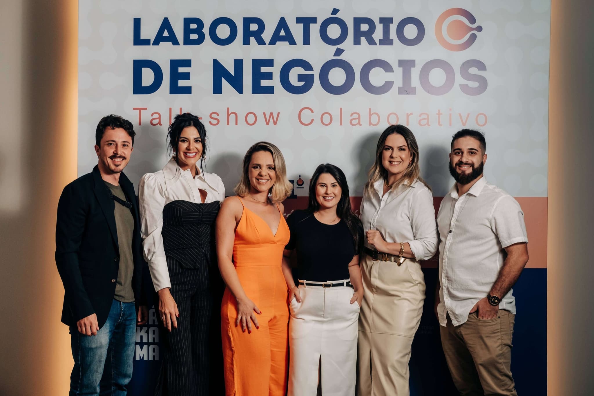 Organizadores e convidados do Laboratório de Negócios posam diante do painel do evento