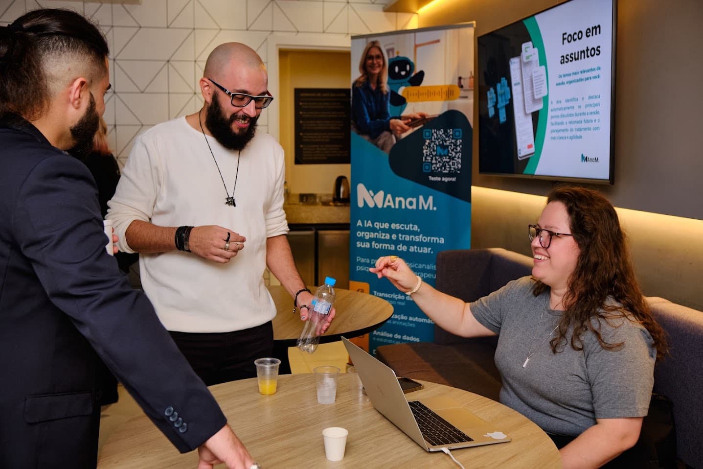 Demonstração da plataforma Ana M para convidadas diante de um banner com QR code